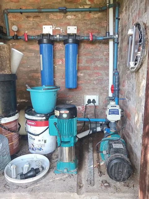 Pressure pumps and a pair of water filters in a brick enclosure after a pump replacement, with the plug point on the wall above